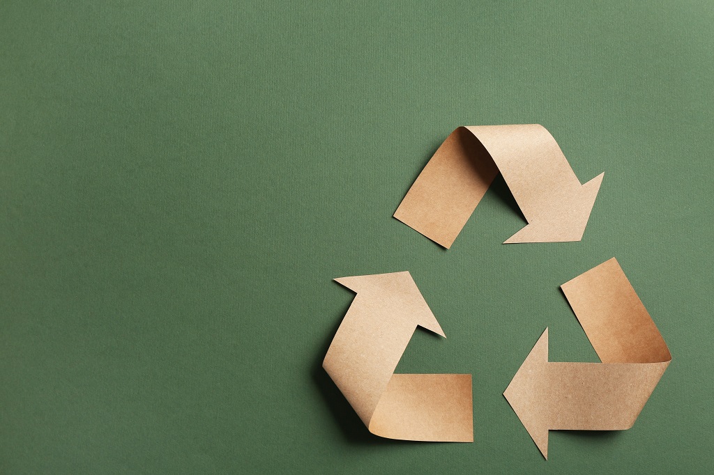 Recycling symbol cut out of kraft paper on green background, top view. Space for text Recycling symbol cut out of kraft paper on green background, top view. Space for text